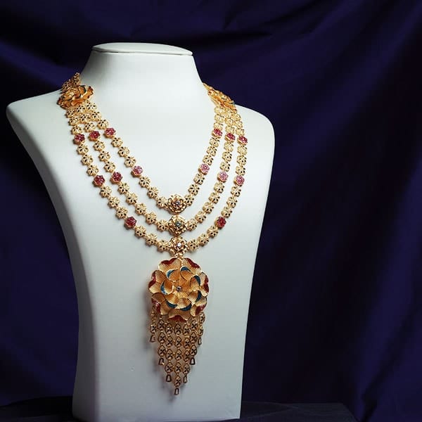 Three-strand 22K gold rani haar with a peacock pendant on a white bust